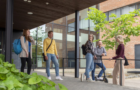 Opiskelijat seisovat Aurora-rakennuksen edessä.
