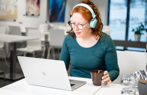 woman studying on a lap top with a cup of coffee in hand