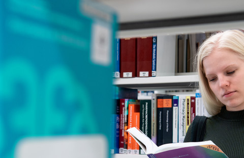 UEF-lähettiläs Mirka Nieminen kirjastossa selaamassa kirjaa