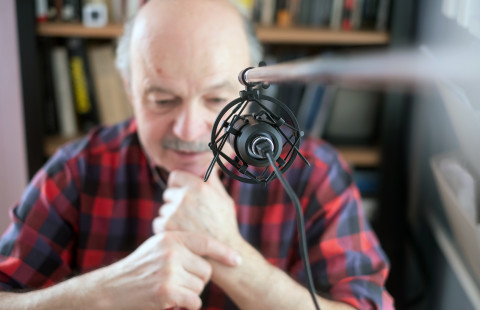 Vanha mies puhuu mikrofoniin.