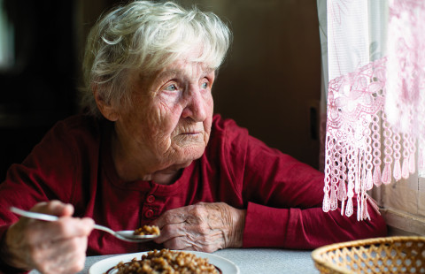Iäkäs henkilö ruokailee kotona.