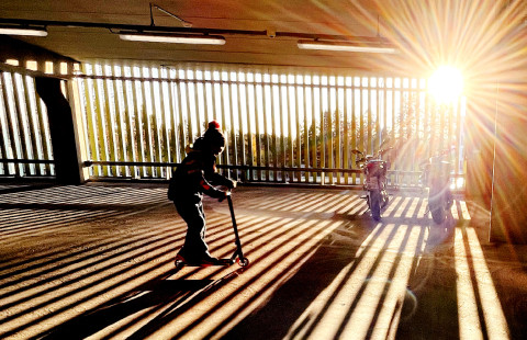 Lapsi potkulautailee parkkihallissa.