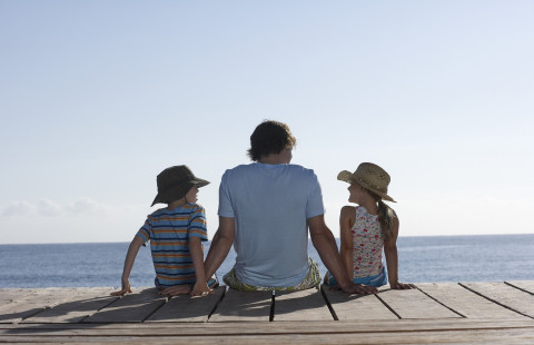 Kolme henkilöä istuu laiturilla.