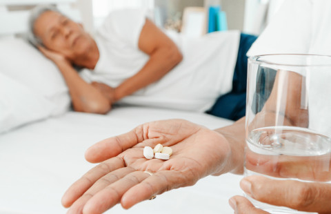 Hoitaja antaa lääkkeitä iäkkäälle henkilölle.