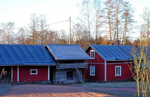 Punaisia rakennuksia ja harmaa aitta maatalon pihapiirissä.