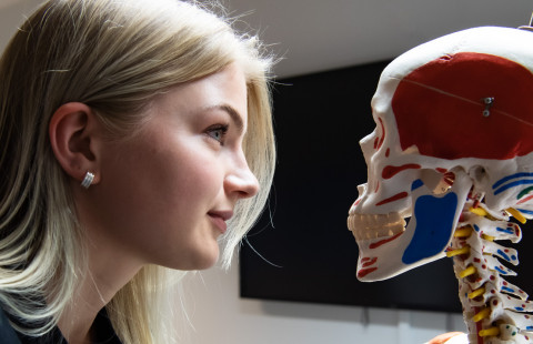 Nainen tuijottaa luurankomallia silmiin.