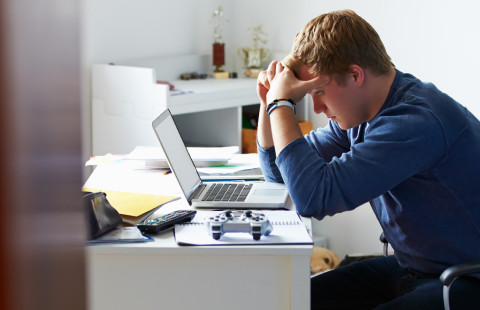 Student leaning on his hands by an office desk.