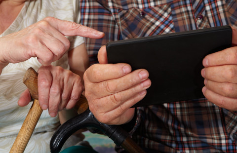 Kahden vanhan ihmisen kädet ja tablet-tietokone.