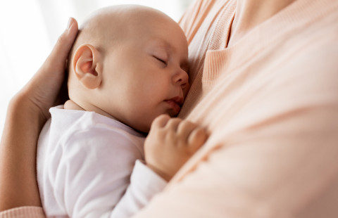 Nukkuva vauva äidin sylissä.