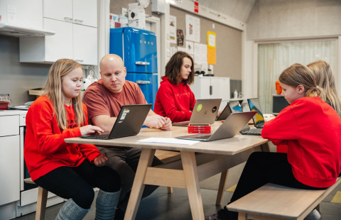 Opettaja ohjaa oppilaita koulutehtävissä.