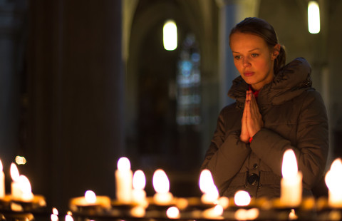 Nainen rukoilemassa kirkossa.