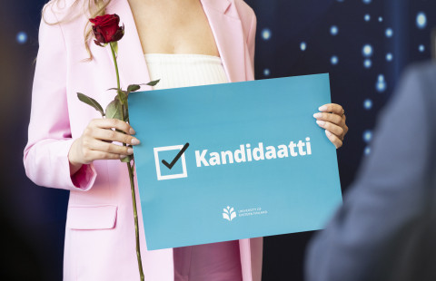 Opiskelija pitää onnittelukylttiä publiikissa.