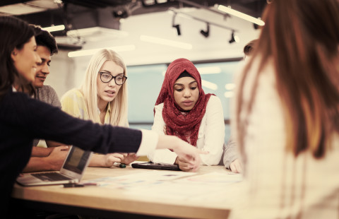 Ihmiset pitävät kokousta pöydän äärellä.