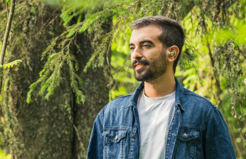 Mies kuuntelee verkkokurssia metsässä