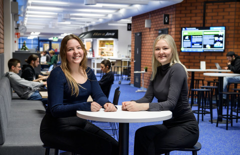 Kaksi opiskelijaa aulassa.