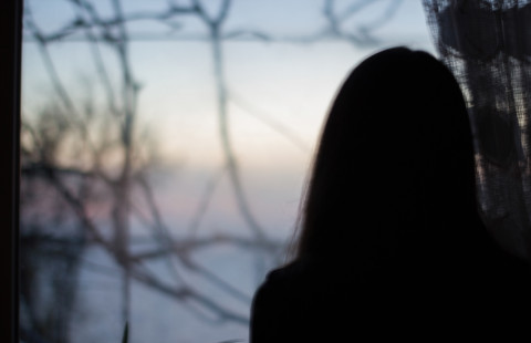 Henkilö katsoo ikkunasta ulos.