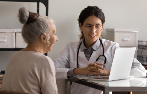 Potilas ja lääkäri tietokoneella.