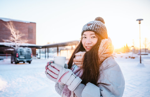 Student in winter ourdoors, holding a coffee cup