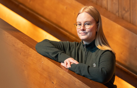 Metsätieteen opiskelija Helmi Karppinen nojaamassa puiseen porraskaiteeseen