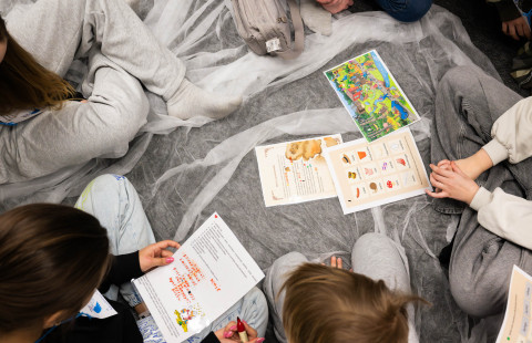 Oppilaat tekevät koulun lattialla ryhmätehtäviä.