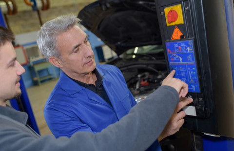 Miehet korjaamassa autoa.