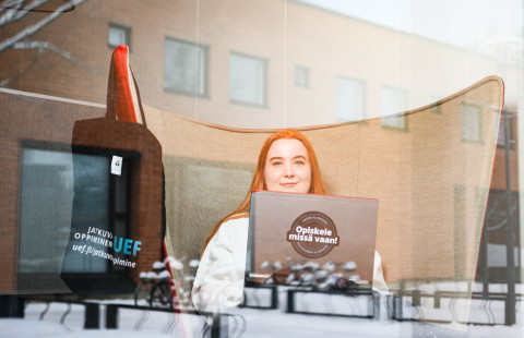 Opiskelija opiskelee ikkunan takana