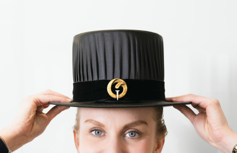 Nainen laittaa tohtorinhatun päähän.