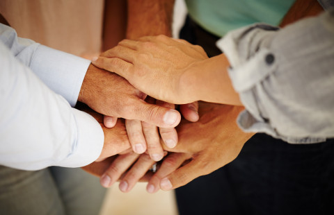 Kädet yhdessä kuvaamassa tiimihenkeä.