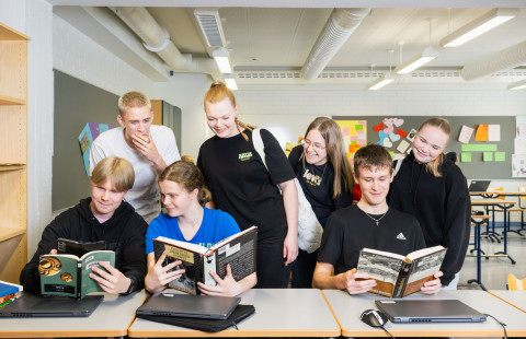 Ryhmä oppilaita tutkii kirjoja yhdessä.