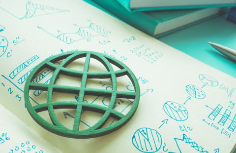 Vihreä maapallo embleemi muistikirjan sivun päällä.