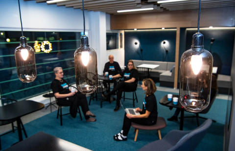 Iloisia ihmisiä opiskelemassa ryhmätyötilassa.