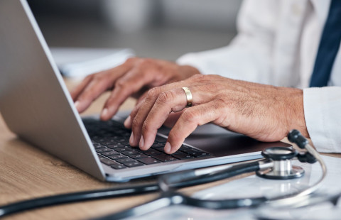 Lääkärin kädet kannettavan tietokoneen näppäimistöllä.
