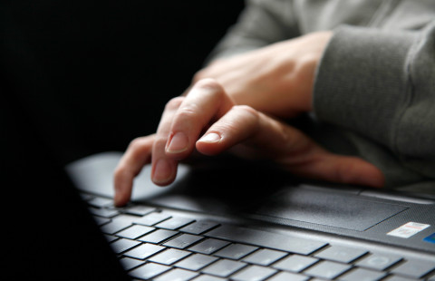 Kädet tietokoneen näppäimistöllä.