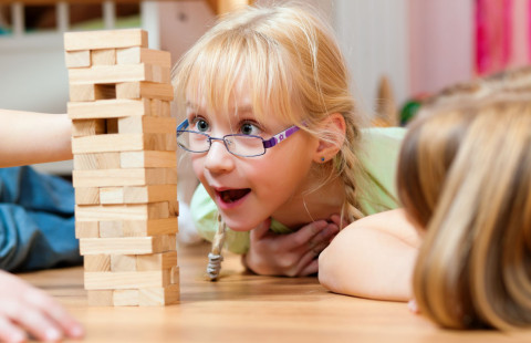 Lattialla makaava lapsi katsoo Huojuva torni -peliä.