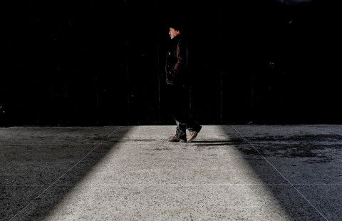 Ihminen kävelee kadulla seinän vierustaa.