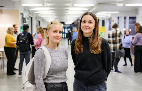 Saara Torpakko ja Miia Prusi seisovat yliopiston aulassa.