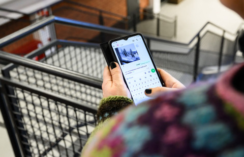 Henkilö päivittää sosiaalisen median tiliään portaikon kaiteen vieressä.