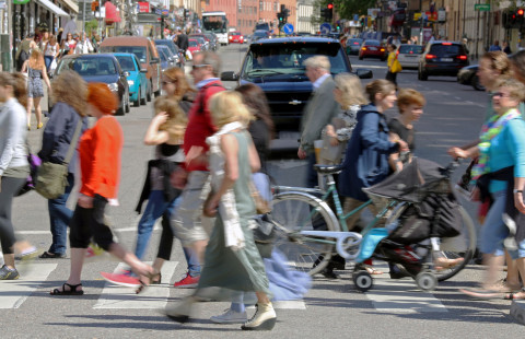 Ihmisiä kävelemässä suojatiellä vilkasliikenteisellä kadulla.