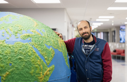 Student leaning on a giant globe