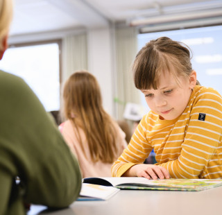 Tyttö lukee kirjaa oppitunnilla.