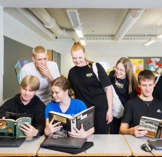 Ryhmä oppilaita tutkii kirjoja yhdessä.