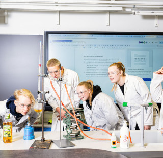 Ryhmä oppilaita tekee laboratoriokoetta luokassa.