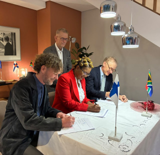 People gathered around a table to sign an agreement.