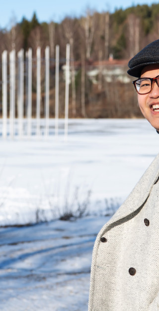 Young man outside in wintery scenery, smiling.