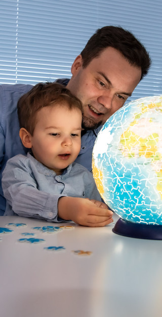 Adult and child playing with a jigsaw puzzle globe.
